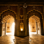 Interior view of a historic Nawabi monument in Lucknow featuring ornate arches, intricate architectural details, and light-filled corridors showcasing Awadhi heritage craftsmanship.