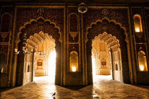 Interior view of a historic Nawabi monument in Lucknow featuring ornate arches, intricate architectural details, and light-filled corridors showcasing Awadhi heritage craftsmanship.
