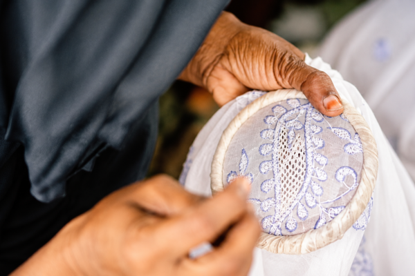 Lucknow artisan creating intricate Chikankari embroidery by hand on fabric using traditional stitching techniques.