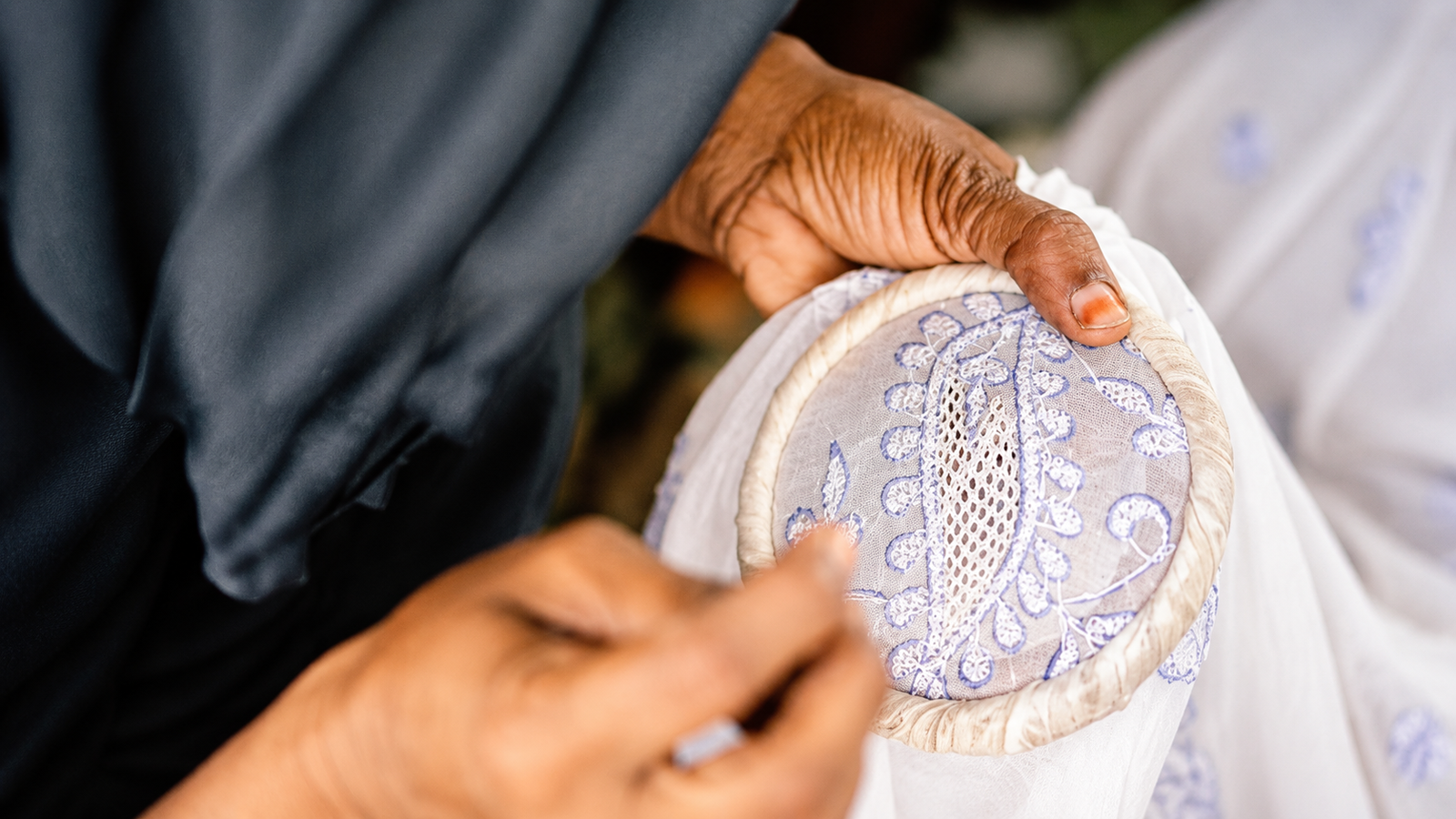Lucknow artisan creating intricate Chikankari embroidery by hand on fabric using traditional stitching techniques.